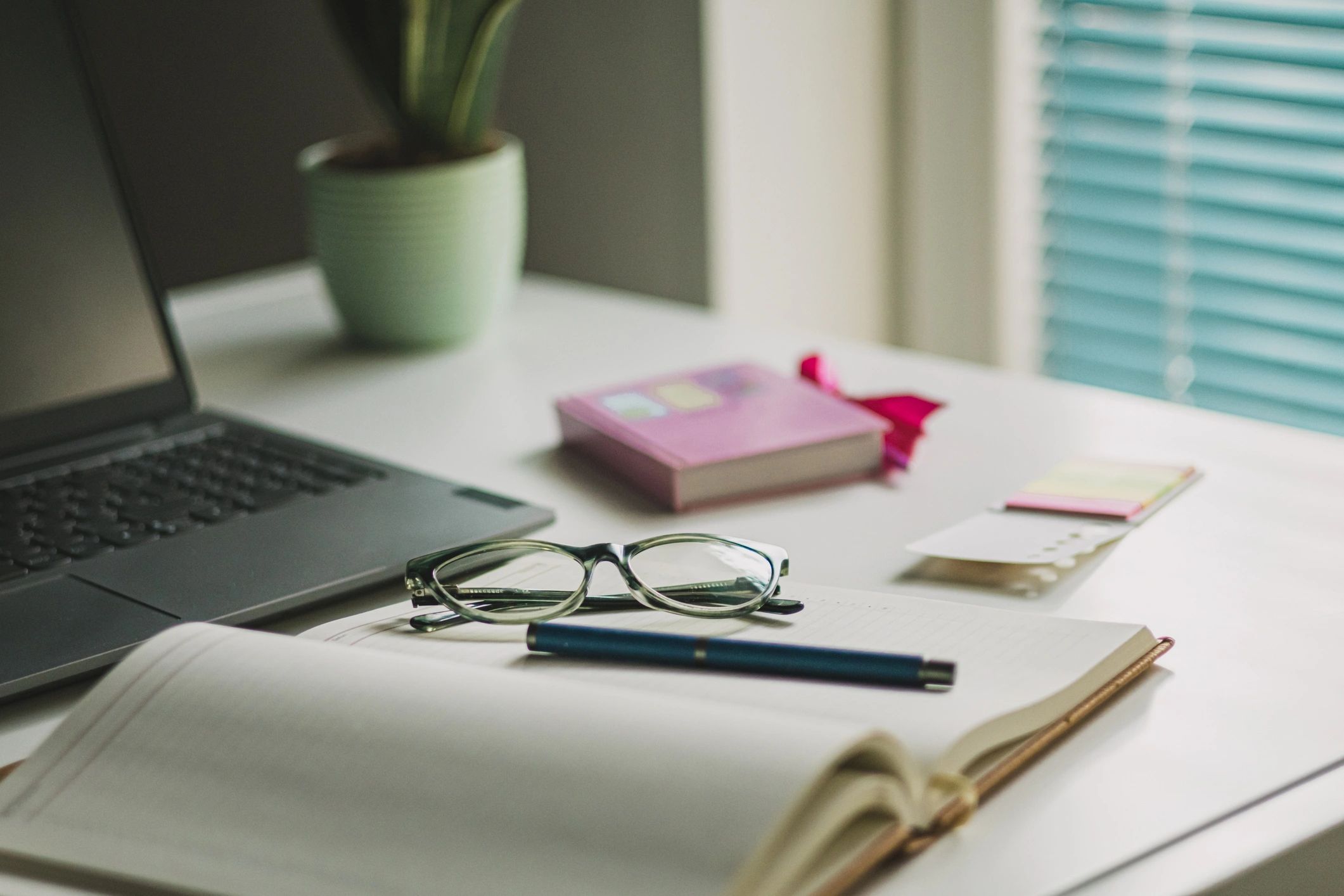 Study desk with laptop, coffee, and reading glasses